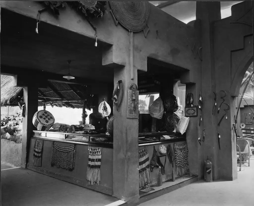 The inside of a building with objects laid out on a table under a shelter such as fabrics and drum.