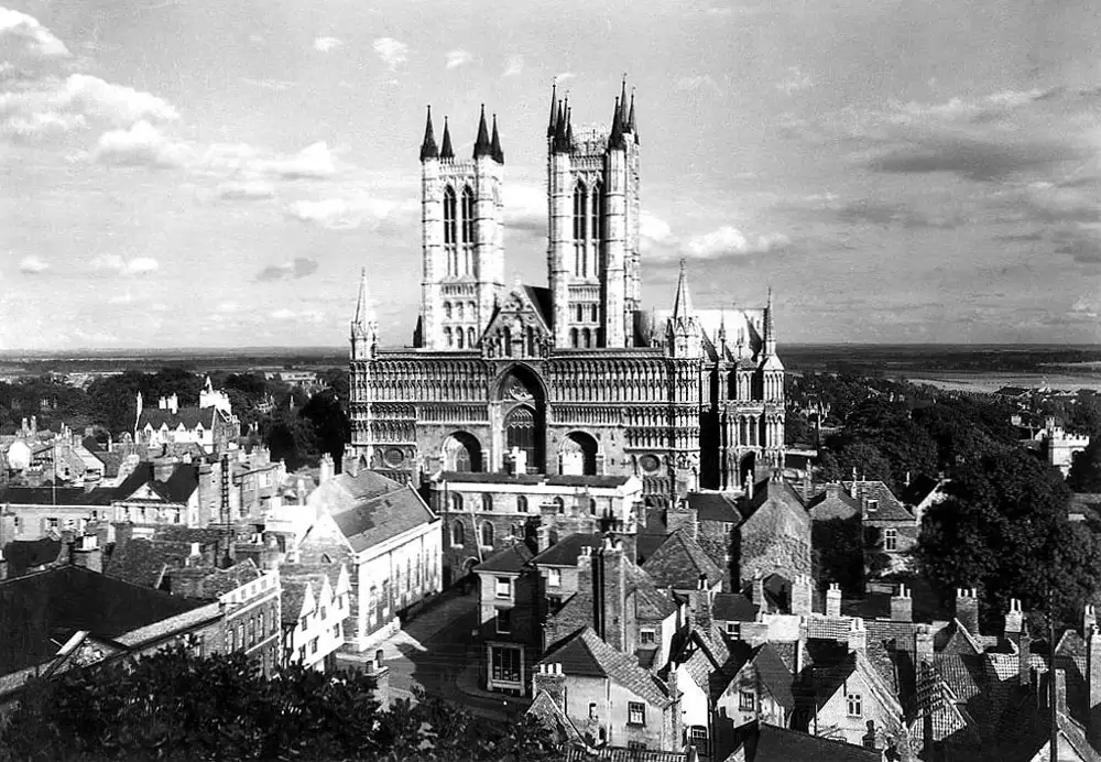 An impressive cathedral buildings with two large towers sticks out from surrounding buildings.