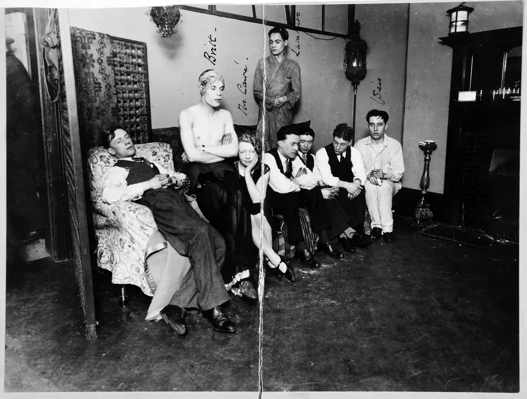 Eight people seated, one standing, in a room looking at the camera.