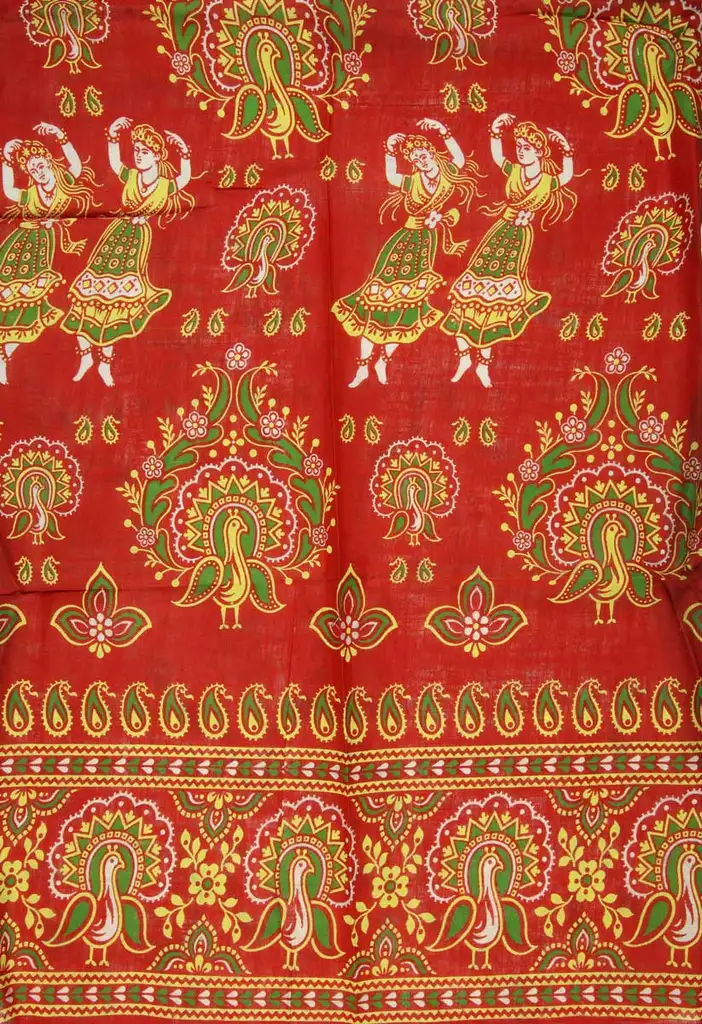 A red textile with yellow and green details including dancing women and a bird.