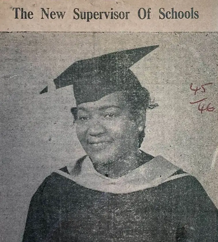 A seated woman wearing a university gown.