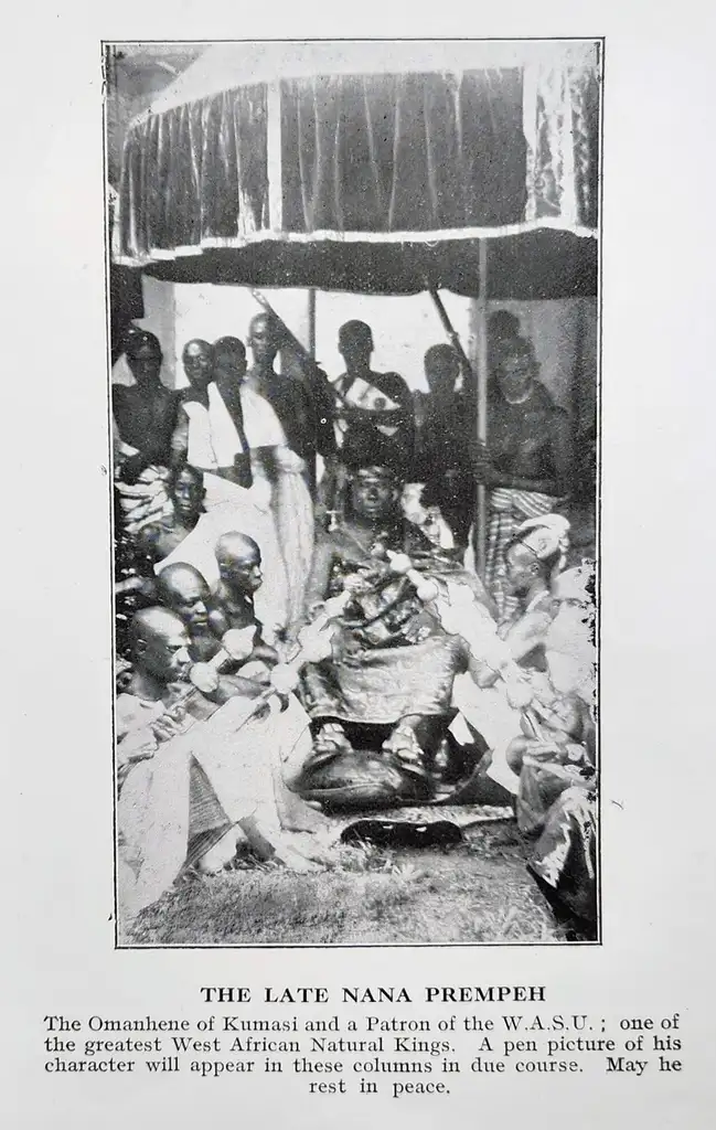 A photograph of a African ruler sat in the middle of around 20 people.