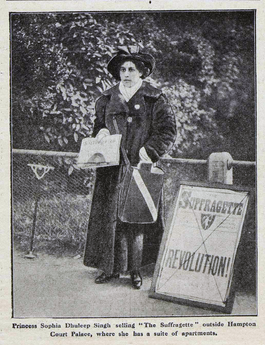 Sophia Duleep Singh standing outside wearing a warm coat selling copies of 'The Suffragette'.