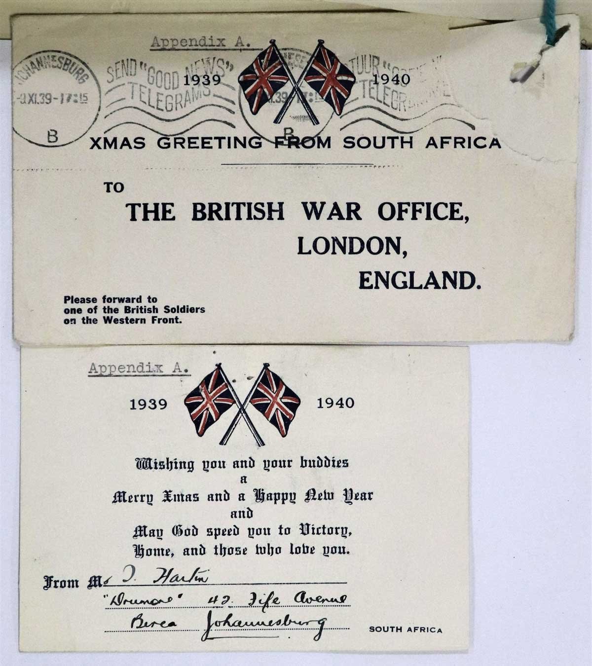 An envelope sits above a card on a page of the war diary. Both have matching British flags on.