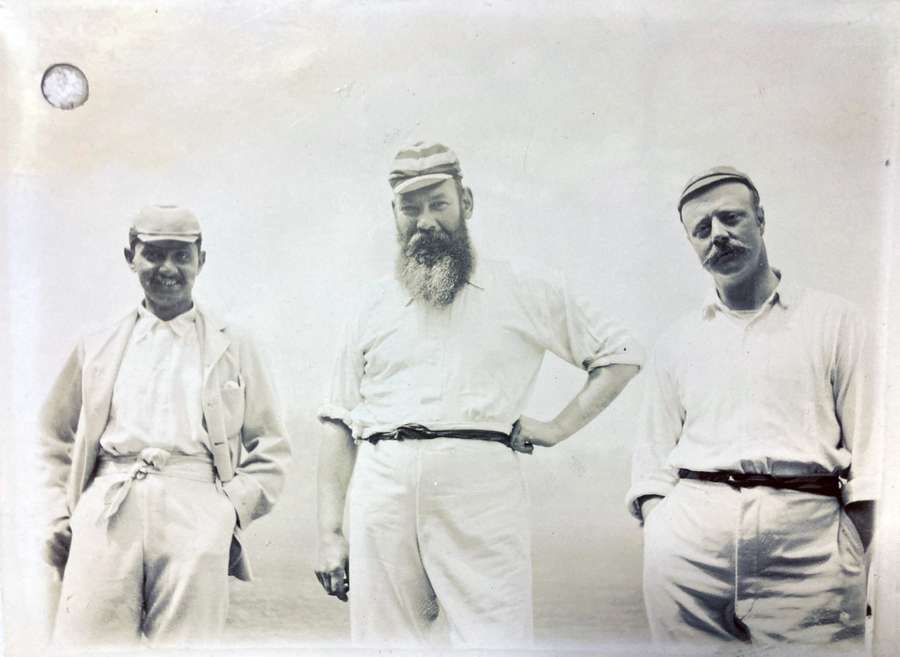 Three cricket players, wearing cricket attire, standing in a line.