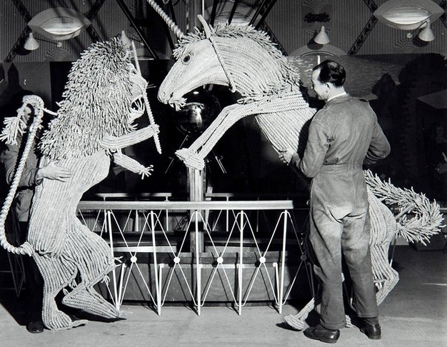 A man works on large straw models of a lion and a unicorn