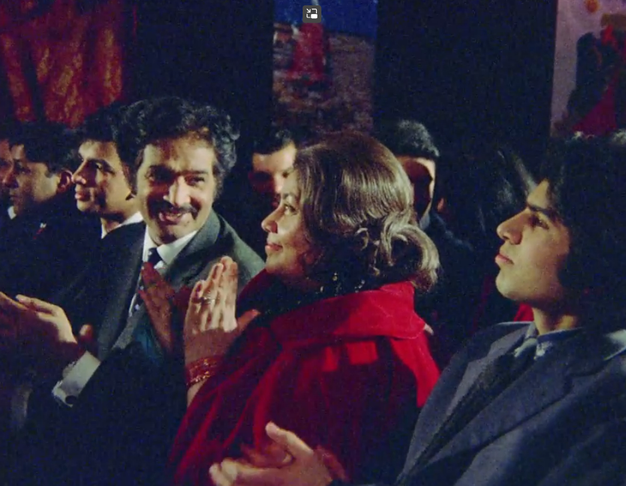 A still from Insaaf. A South-Asian family sit in a theatre watching the stage