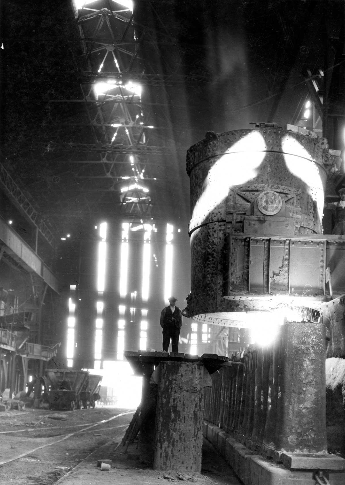 A man in a vast warehouse stood on a platform next to a huge metal cylinder.