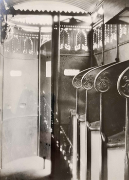 Black and white photo of urinal stalls and light flooding in from a gap below the roof.