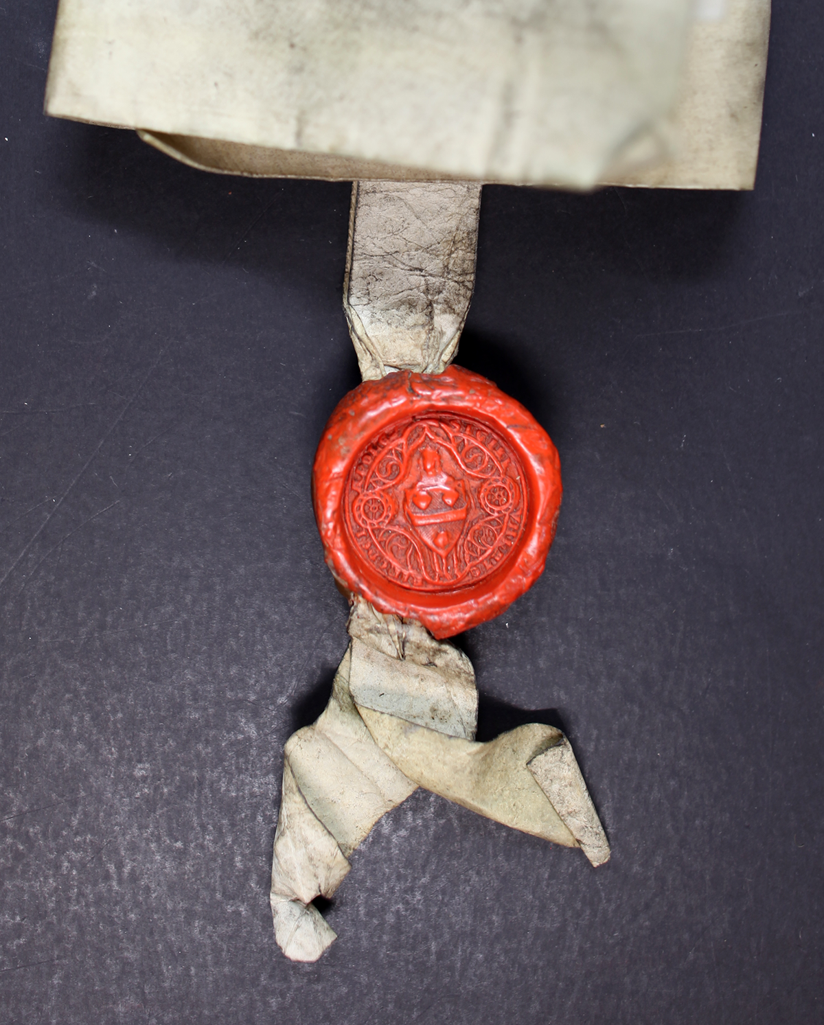 Close-up of a finely detailed wax seal attached to a folded document.