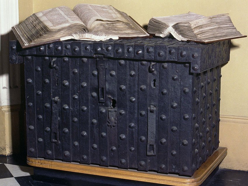 A large dark metal chest with studs. Two books are resting on top