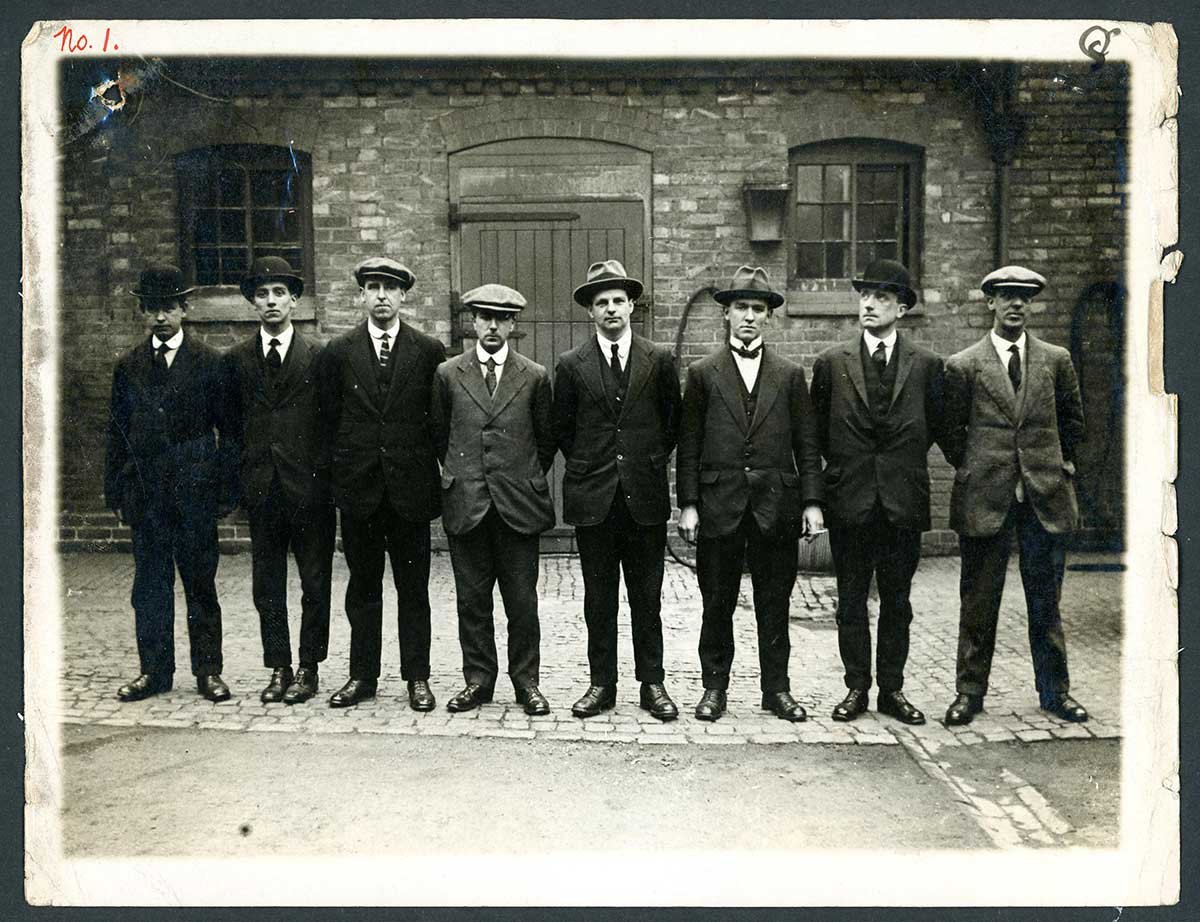Photograph of eight men standing in a line.