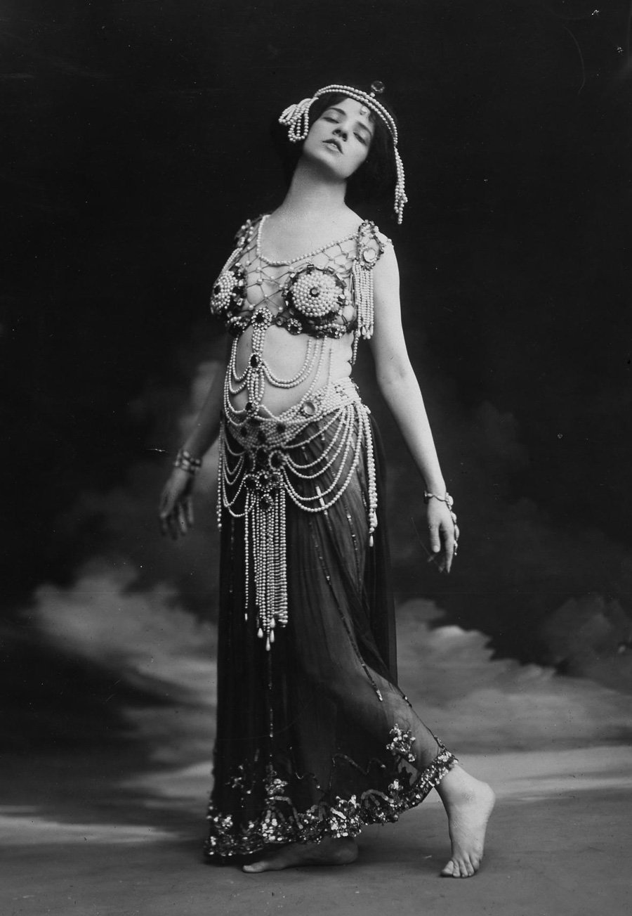 A photograph Allan dressed as Salome. She wears a beaded cropped top and translucent skirt