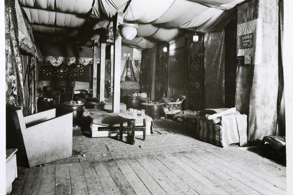 The interior of a club with no people. It is full of soft furnishings, tables and draped fabric