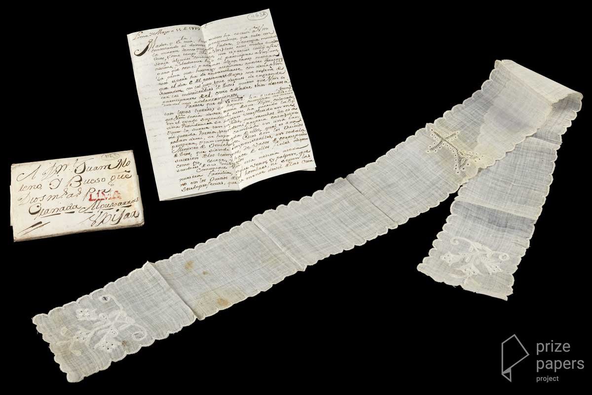 A long, folded-over strip of linen below a folded letter and an envelope with Spanish writing on.