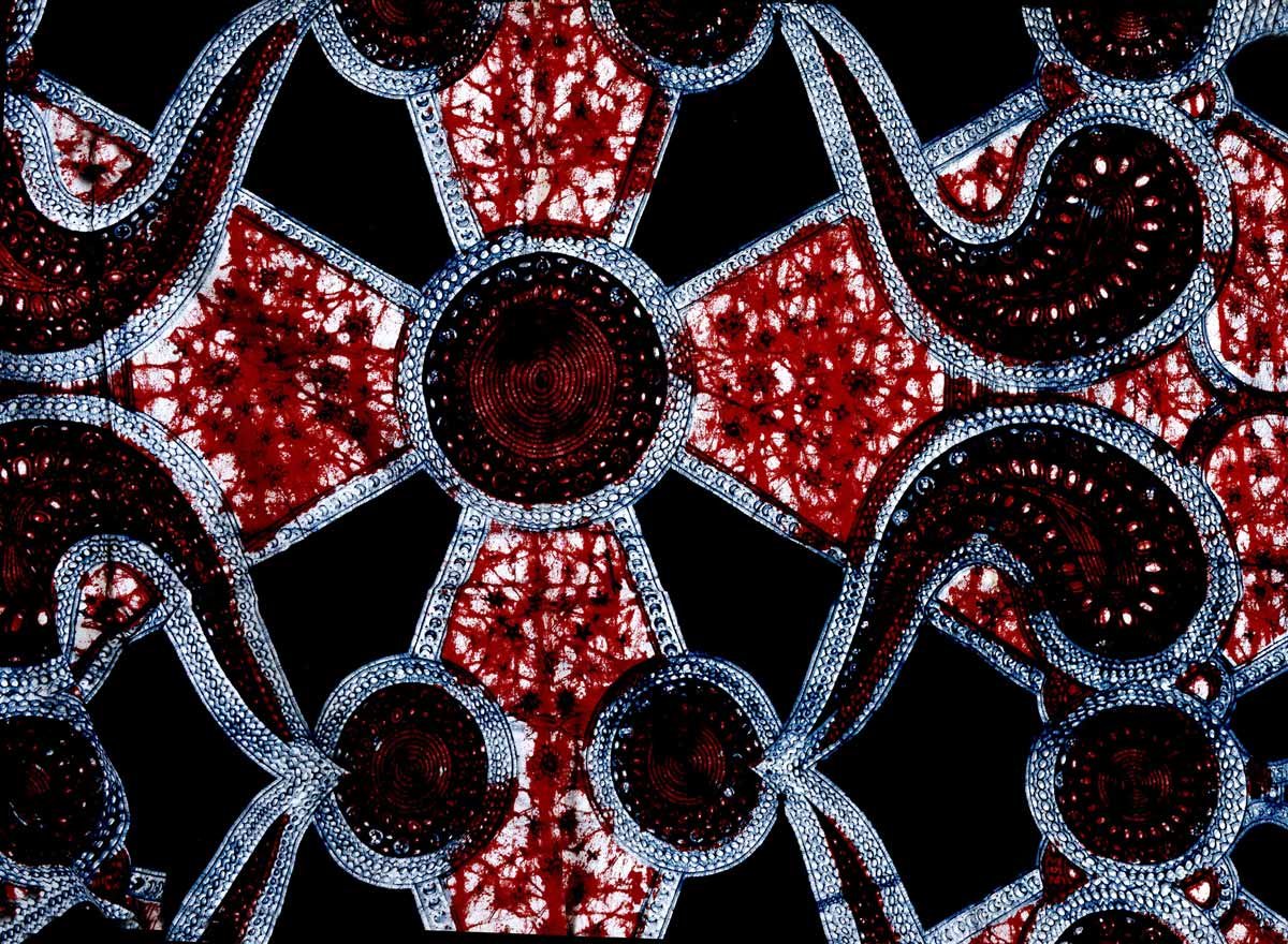 A black textile with a red cross like shape with circles and waves.