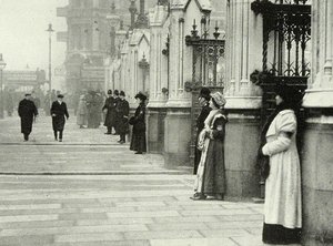 A photo of two women standing besides pillars outside the House of Commons. Police are watching on.