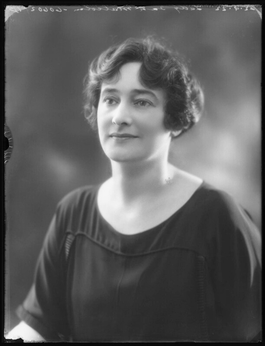 Portrait photo of a woman with short, wavy hair, wearing a dark blouse.