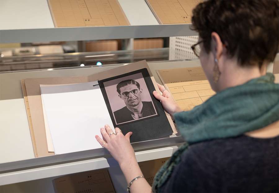 A woman holds open a file and looks at a photograph.