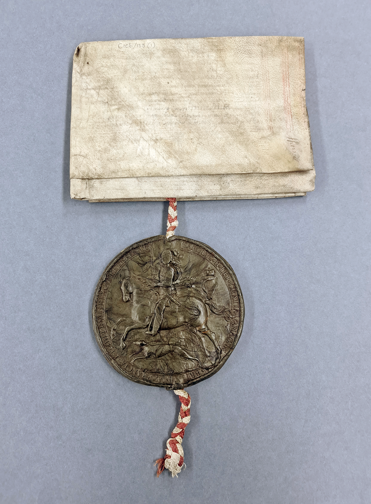 A folded sheet of paper with a large, round, brown wax seal attached with red and white cord.