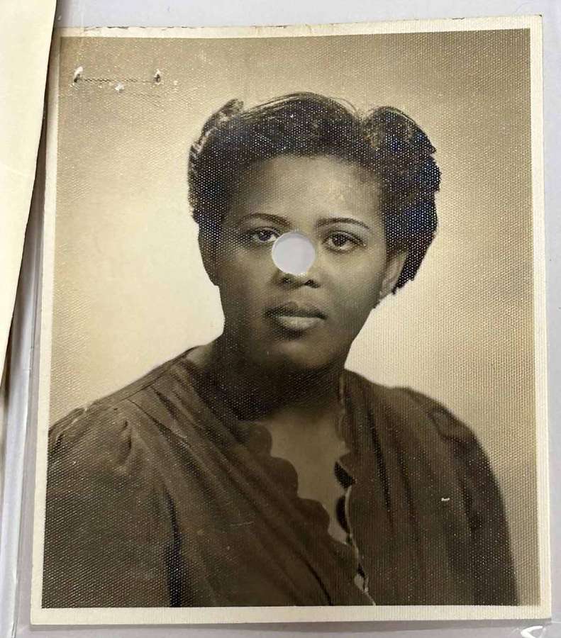 Portrait photo of Louise with a neutral expression. It has a hole punched in the middle.