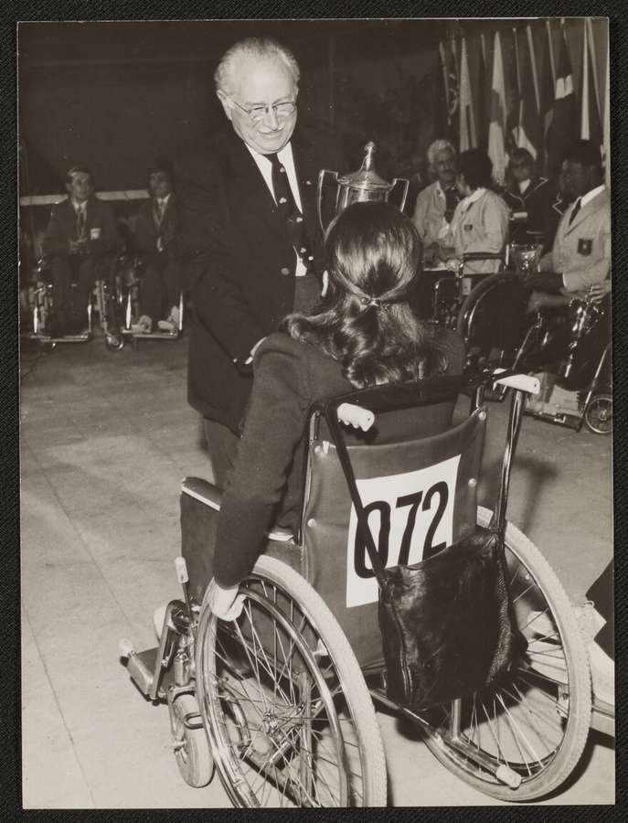 Sir Ludwig Guttmann speaking to an athlete in a wheelchair.