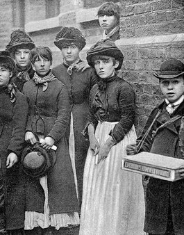 A group of young working class women stand together looking directly at the camera
