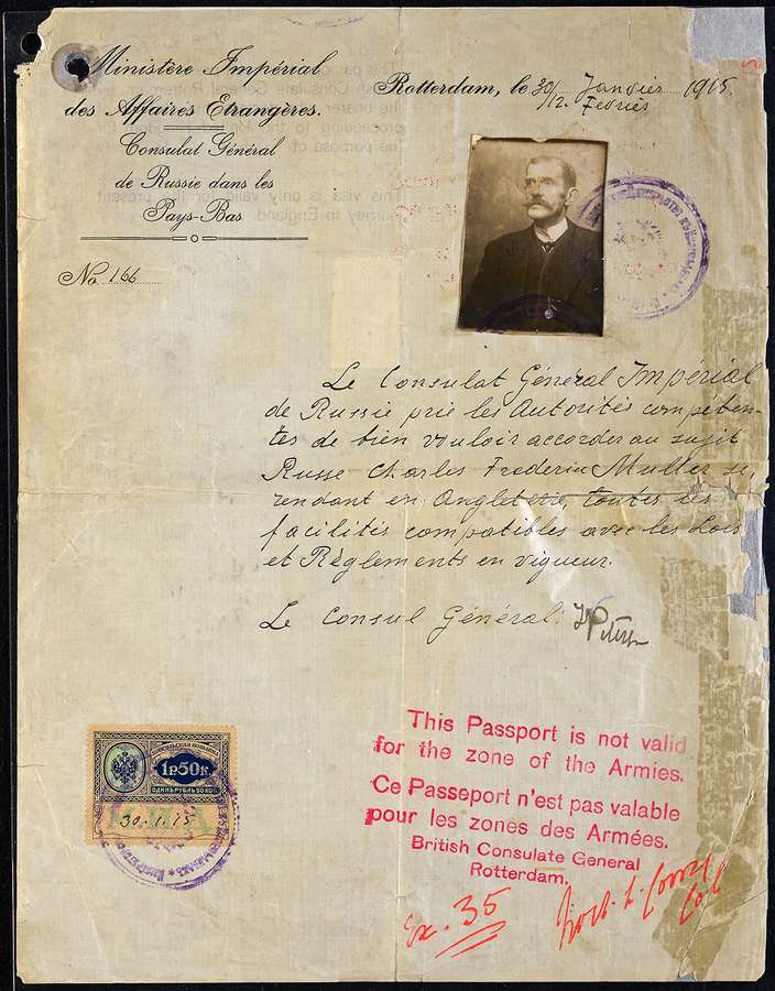 A frayed yellow sheet of paper with a photo of a man, a stamp, and both handwritten and printed text