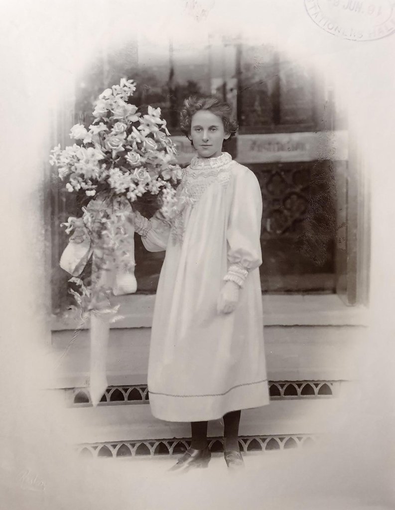 Sepia photograph of a young woman with a faint smile holding a bouquet of flowers.