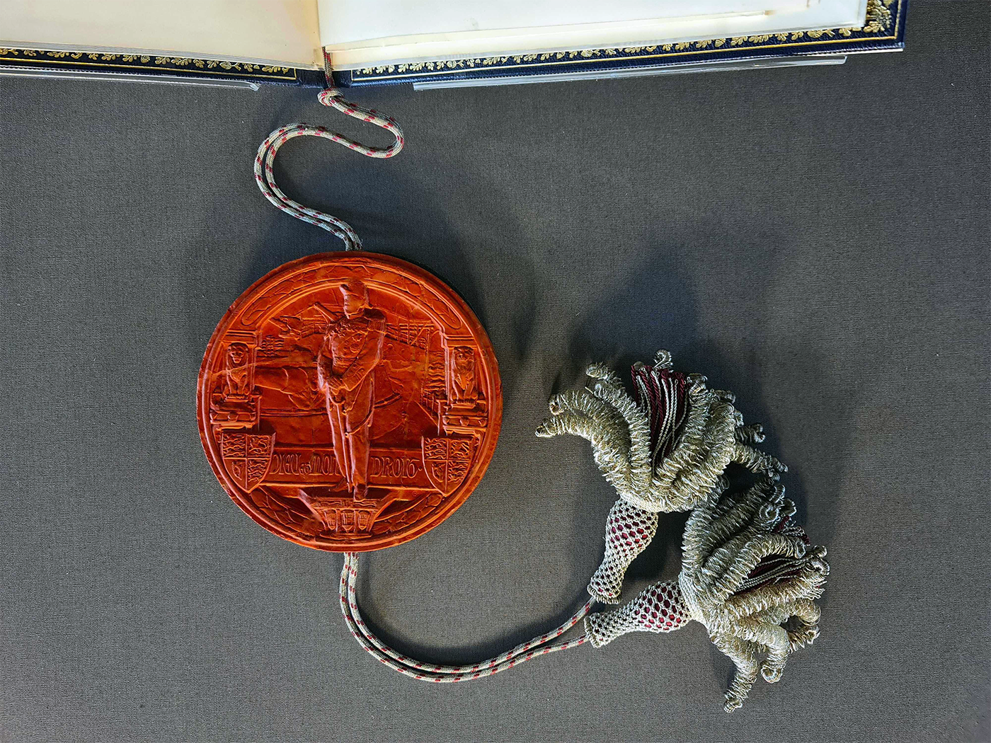 The bottom of the volume with a large, patterned red circle attached with string and tassels.