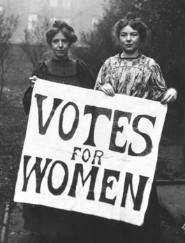 Suffragettes Annie Kenny and Christabel Pankhurst holding a giant sign that says Votes for Women.